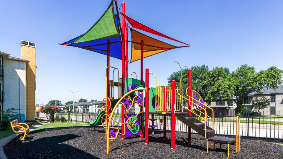 a colorful playground with a slide and swings at The  Dahlia